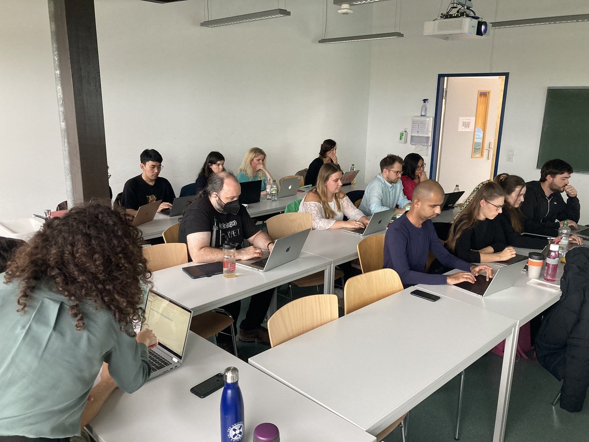 The audience is shown in this picture: 14 people following the workshop on their laptops. On the left, Dr. Shira Tal is talking to a member of the audience, gesturing at their laptop.